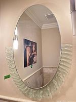 Full view of oval mirror mounted on wall showing decorative clear glass rim