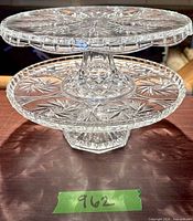Both clear glass cake stands stacked to show size difference and pedestal bases