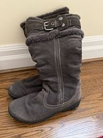 Full side view of both boots showing suede exterior, zipper, buckle strap, faux fur trim