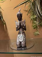 Front view of kneeling Buddha statue showing prayer pose and mosaic details