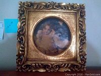 Front view of the square gold gilded ornate frame with round ceramic artwork depicting Victorian children