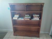 Front view of wooden bookshelf showing four shelves with various books on the middle shelves