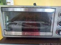 Front view of Oster convection oven with glass door showing included wire rack and baking pan inside.
