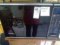 Front view of Kenmore microwave oven with brand visible and dimensions noted on attached paper.