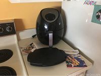 Full view of Zeny air fryer on kitchen counter with recipe book and micro grill cooking guide placed beside it, showing size and included materials.