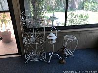 Three white metal outdoor decorative pieces: folding corner shelf unit, lantern on stand, and small plant stand.