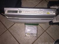 Top view of silver Sony under cabinet CD player and radio with control buttons and CD slot.