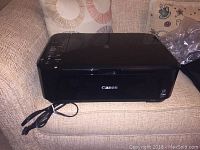 Canon MG3120 multifunction printer closed, showing top, side control panel, power cable, and Canon logo