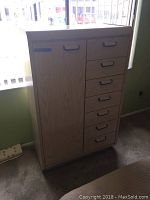 Front view of the wooden armoire showing seven drawers on the right and a cabinet door on the left