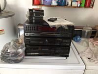 Pioneer stereo receiver, CD player, and cassette deck stacked on a white surface with cables bagged beside them.