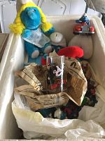 Top view of box showing Plush Smurfette, plastic Smurf car toy, ceramic money box, and glass with Mickey design.