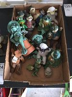 Box with a total of twelve frog figurines of various sizes and two small sheep figures grouped together.