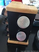 Side view of the spice rack showing two metal spice shakers on the side and the beech wood top and base.