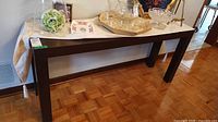 Full view of dark brown console table with decorative items on top