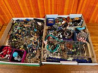 Two boxes filled with assorted costume jewelry pieces