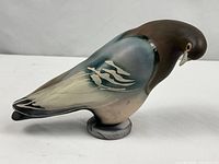 Full left-side view of ceramic bird on round base