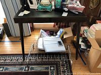 Photo showing the wood table with a dark finish, slightly tapered legs, and decorative inlaid top pattern. Top surface visible with some minor natural wear.