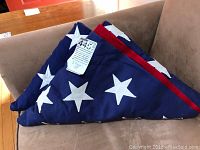 Two US flags folded in triangular shape showing white stars on blue field and edges of red stripes.