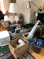 Photo showing various lamps, plastic drawer organizer, box with cords, wastebaskets, and metal storage cases in background