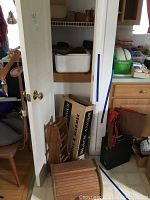 Wooden portable bar components including bread box, folded wine rack, and Black Angus griddle and warmer boxes stacked beside a door.