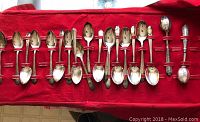 Full assortment of vintage Wm. A Rogers silverplate spoons and ladles with detailed ornate handles laid on red cloth