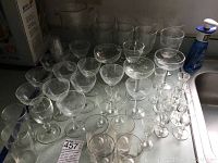 Photo showing a collection of various clear glassware including stemmed glasses, a glass pitcher, and other assorted glasses.