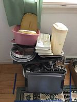 Full lot view showing stacked items including baking pans, pots, plastic tubs, and ice cube trays.