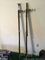Full view of two metal bed frame side rails standing against a wall on green carpet.