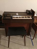 Sears electric digital piano with wood frame and control panel above the keys in basement setting.