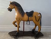 Side view of full horse on base showing overall form, wheels, saddle and mane