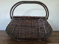 Front view of dark-stained wicker basket with handles raised