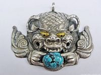 Front view of sterling silver Chhepu dragon pendant showing turquoise stone and gold eyes