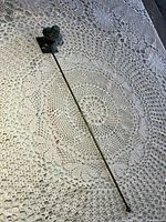 Full view of 13-inch metal candle snuffer on lace surface