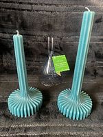 Two teal candles with holder front view