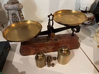 Full view of balance scale with brass pans and weights in front