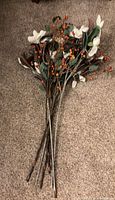 Bundle of long artificial magnolia stems with berries laid on carpet
