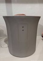 Rear view of cylindrical light gray towel warmer showing two-button control panel and power cord