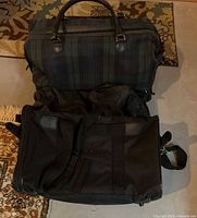 Top-view of plaid duffel stacked on black rolling suitcase