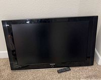 Front view of Samsung TV with screen off and remote placed in front