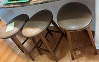Three wooden bar stools under counter