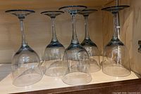 Five stemmed wine glasses inverted on shelf