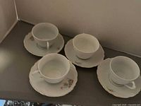 Four porcelain pieces: teacups and saucers with rose pattern