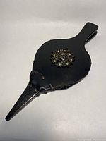Front view showing black wood bellows with brass medallion and metal nozzle
