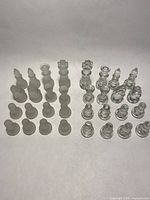Complete set of clear and frosted glass chess pieces arranged by color