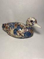 Left side view of ceramic duck figurine showing floral decoupage and crackle glaze