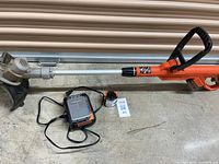 Full view of LST300 trimmer/edger with charger, spare battery, and replacement spool