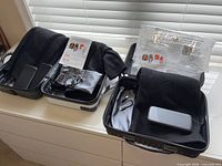 Three open carry cases showing black heated garments, power banks and manuals