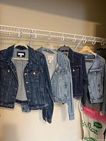 Four denim jackets hanging on rack