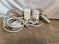 Group of cords, power strips, wall taps piled on carpet