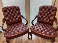 Front view of both burgundy leather armchairs showing overall design and condition